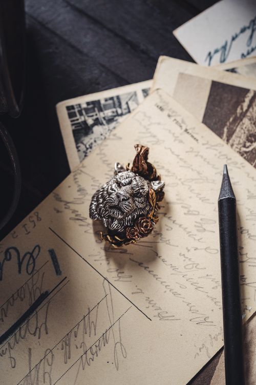 Free Antique lion pendant resting on nostalgic postcards with pencil, evoking a vintage essence. Stock Photo