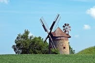 在晴朗的蓝天下，迷人的老风车坐落在郁郁葱葱的绿色乡村中