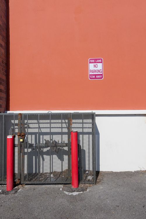 Free A fire lane with a no parking sign and shadow play on an orange wall in an urban setting. Stock Photo