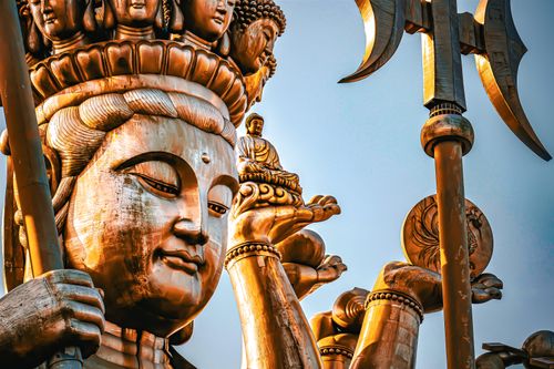 Free Close-up of a golden Buddha statue with intricate details set against a clear blue sky. Stock Photo