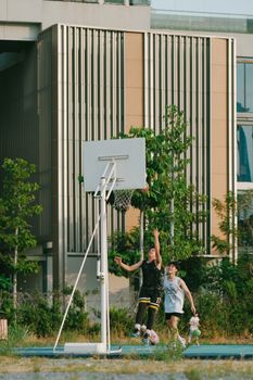 Two teenagers enjoying a basketball game on an outdoor court in a city environment.