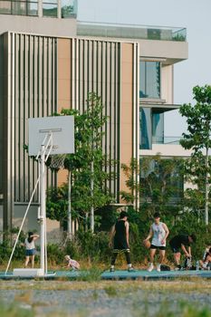 People playing basketball outdoors near a modern building. Urban sports scene.