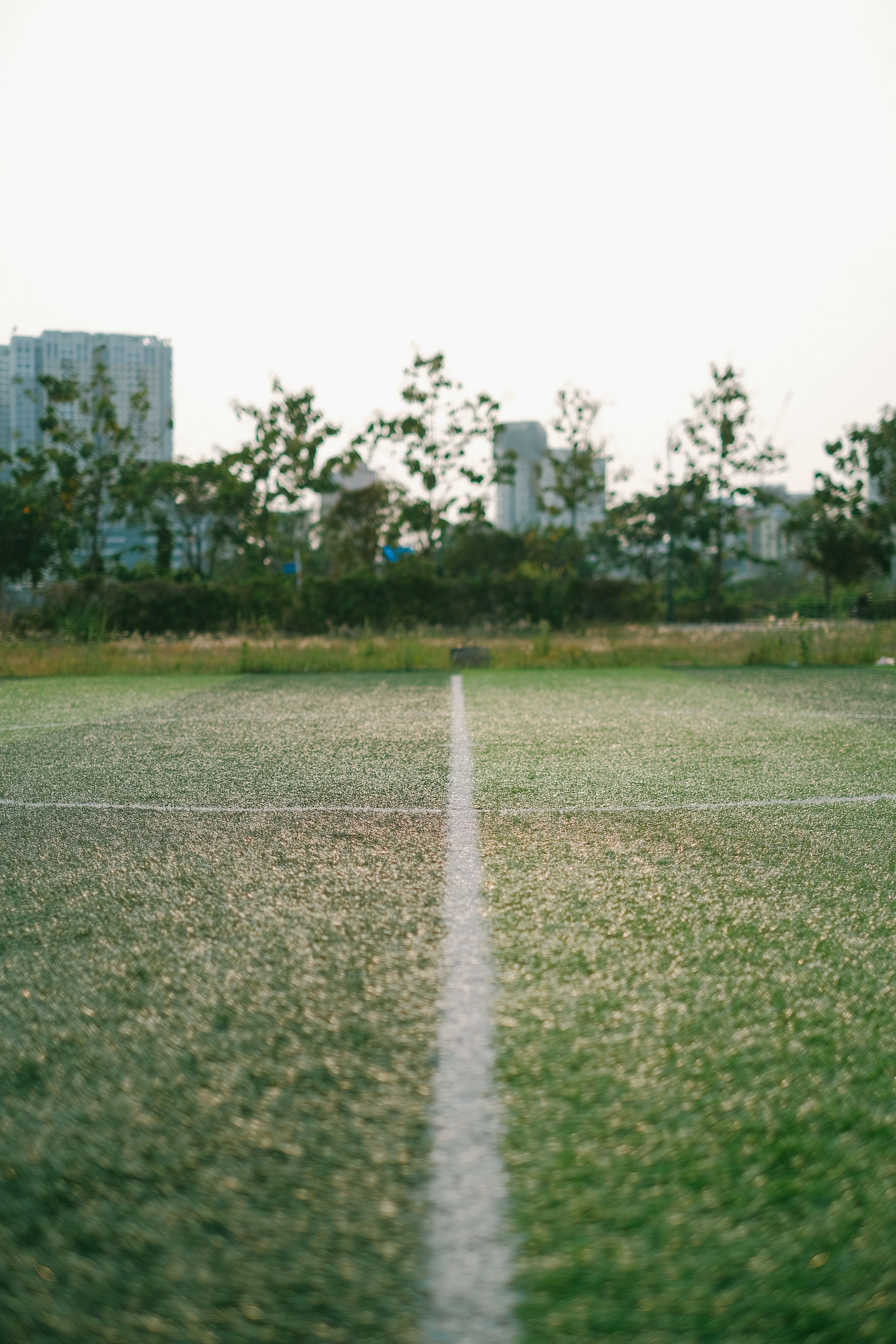Football pitch with white line amidst cityscape, ideal for sports themes.