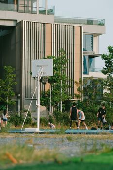 Group of people playing basketball outdoors in an urban setting with modern architecture.