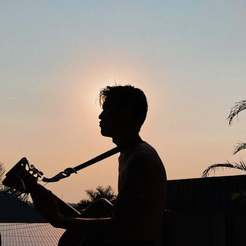 Silhouette of Man with Guitar at Sunset