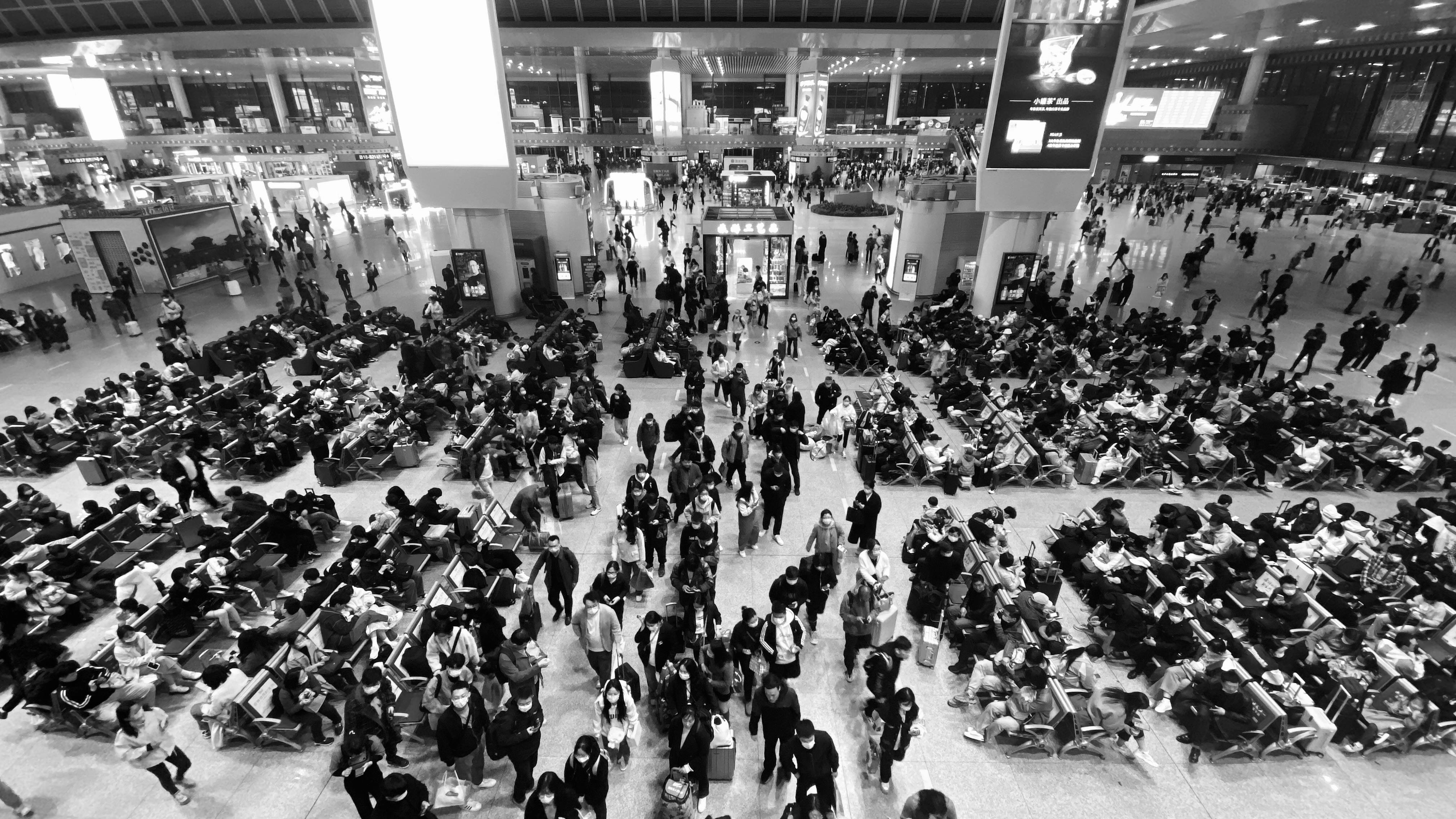 Crowd of people walking and sitting in a bustling airport terminal, high angle view.