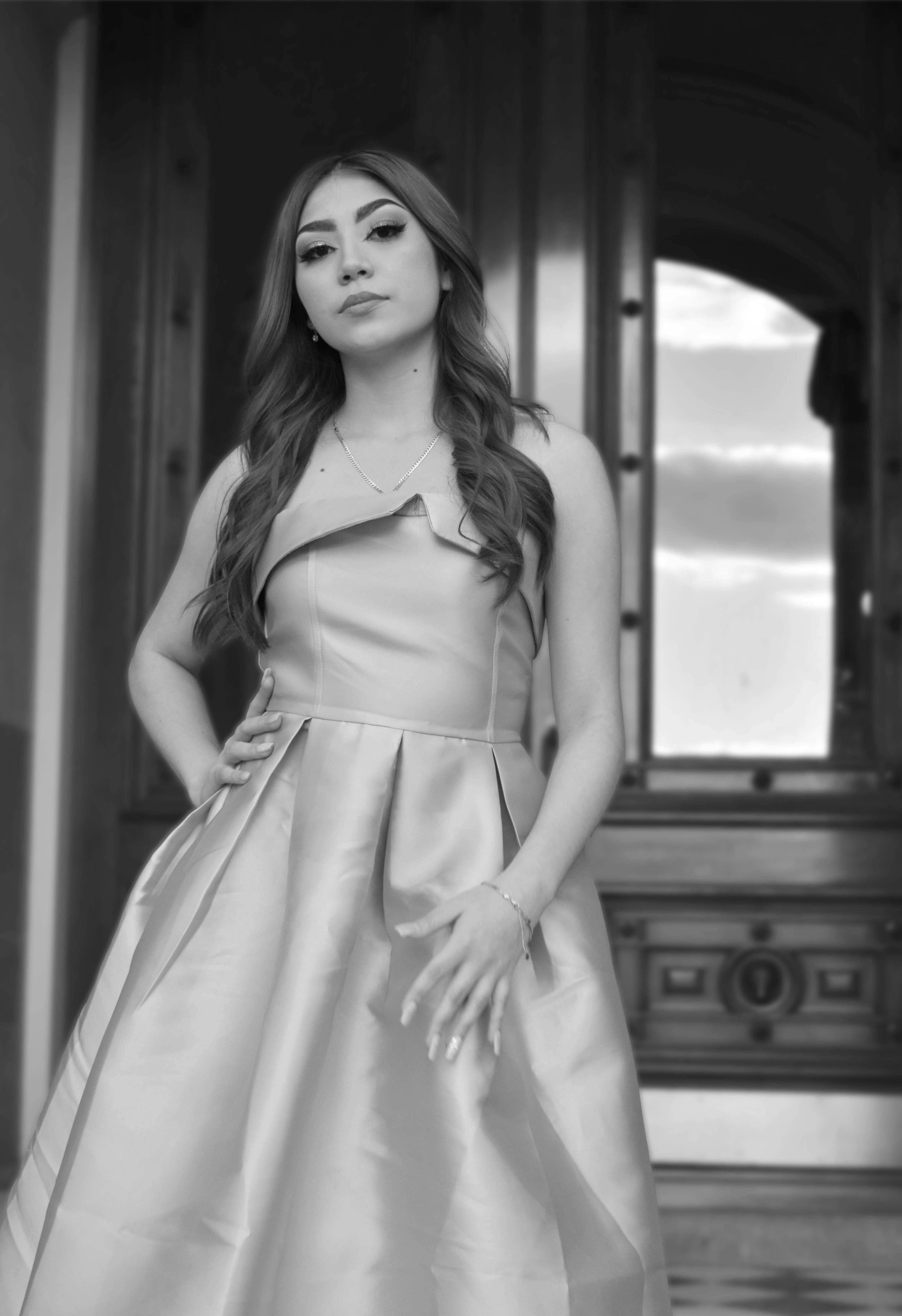 Black and white portrait of a woman in a formal dress with long hair, posing confidently.