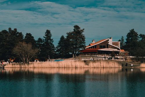 Free Beautiful lakeside lodge surrounded by lush trees and calming waters, perfect for relaxation. Stock Photo
