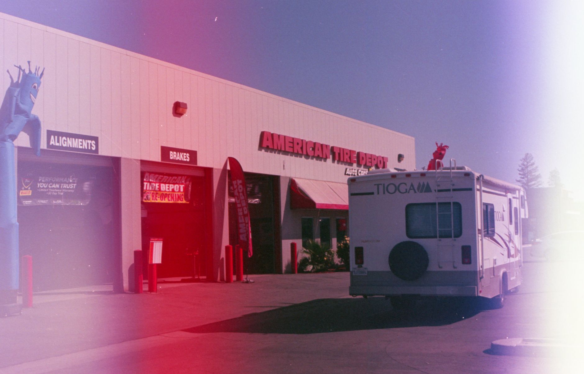 RV parked outside an American Tire Depot building under clear skies