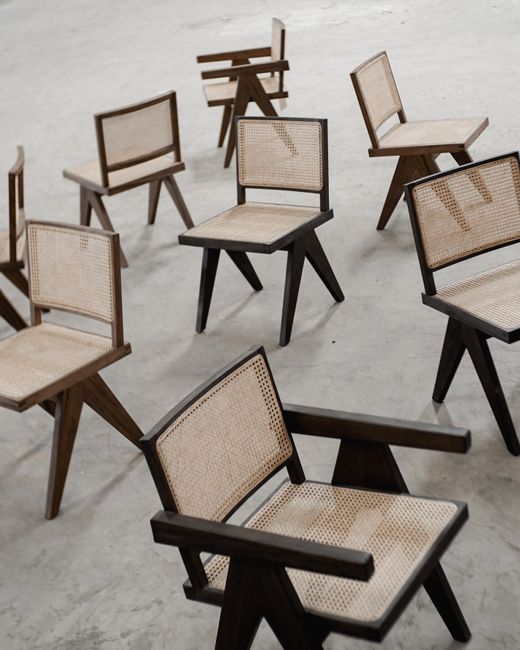 A collection of stylish wooden chairs with woven seats on a concrete surface.