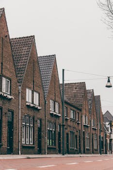 A row of classic brick townhouses lined up on a tranquil urban street, showcasing timeless architecture.