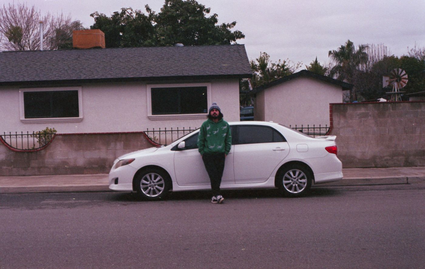Dueño mexicano junto a su auto afuera de su casa