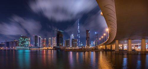 Free Stunning night view of Dubai skyline featuring the illuminated Burj Khalifa and reflections on water. Stock Photo