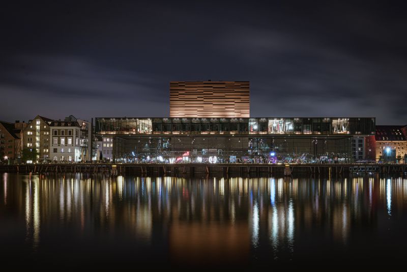 Modern waterfront building lit at night, reflected in the water — photo by Gije Cho on Pexels