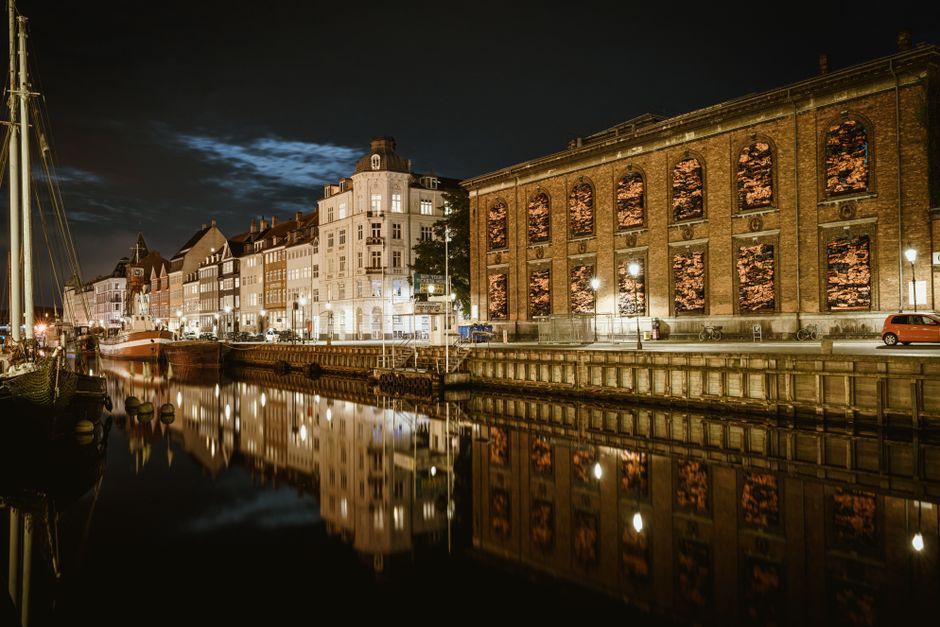 Scenic view of illuminated historic buildings by the canal in Copenhagen at night.