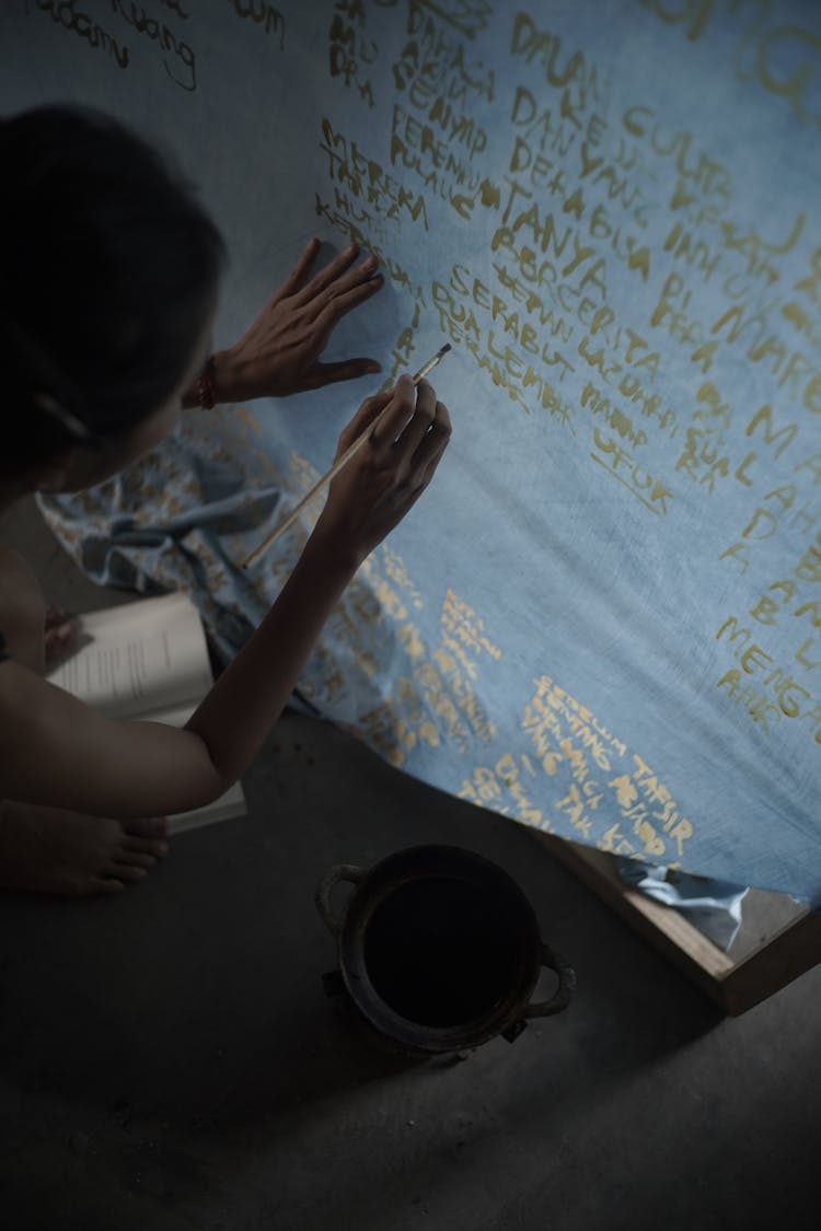 Person Writing With Paintbrush On Canvas