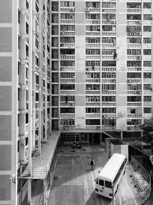 Free Monochrome image of a tall urban residential building exterior with surrounding structure. Stock Photo