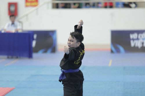 Free Young boy in martial arts uniform performing a pose during a competition indoors. Stock Photo