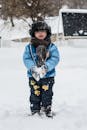 冬天，一个孩子裹好衣服，在外面玩耍，准备打雪仗