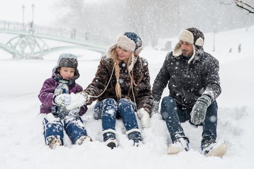 Woman, Man and Girl Sitting on Snow