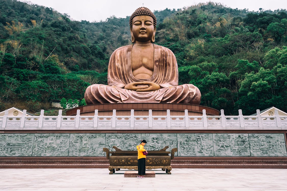 Free Woman Standing by Altar outside of Temple with Buddha Sculpture on Roof Stock Photo