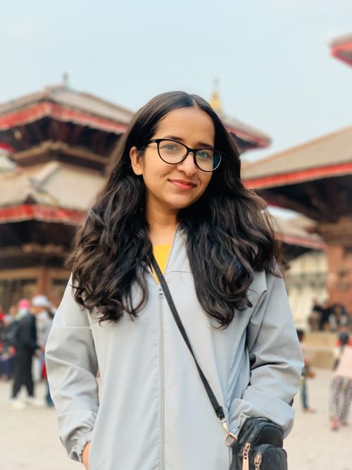 Free Portrait of a young woman in eyeglasses smiling at a historical temple complex. Stock Photo