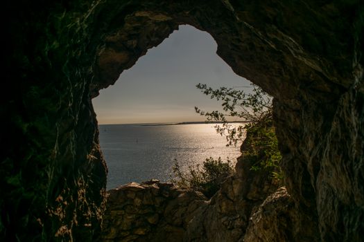 A mesmerizing view of the sea through a natural cave formation at sunset.