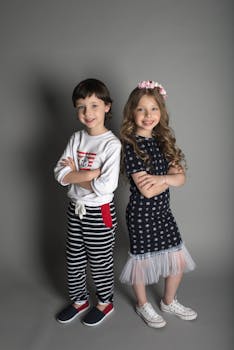 一对穿着时尚服装的可爱男孩和女孩在室内自信地微笑着摆姿势