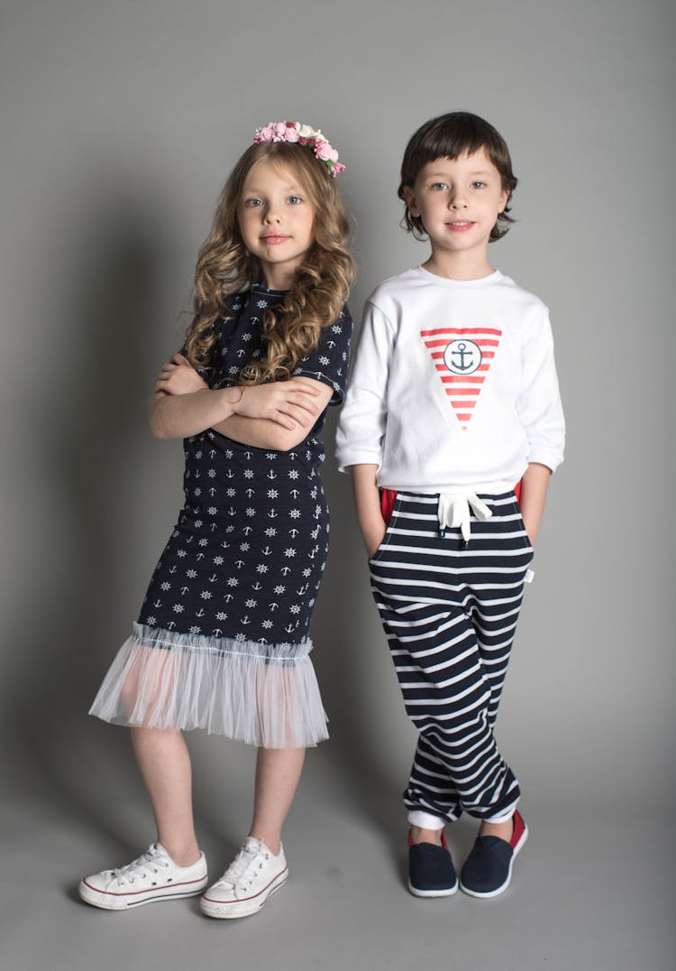 Girl In Black Dress Standing Beside Girl In White Sweatshirt And Black Striped Pants