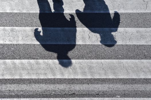 Top view shadows of people walking on an urban zebra crossing