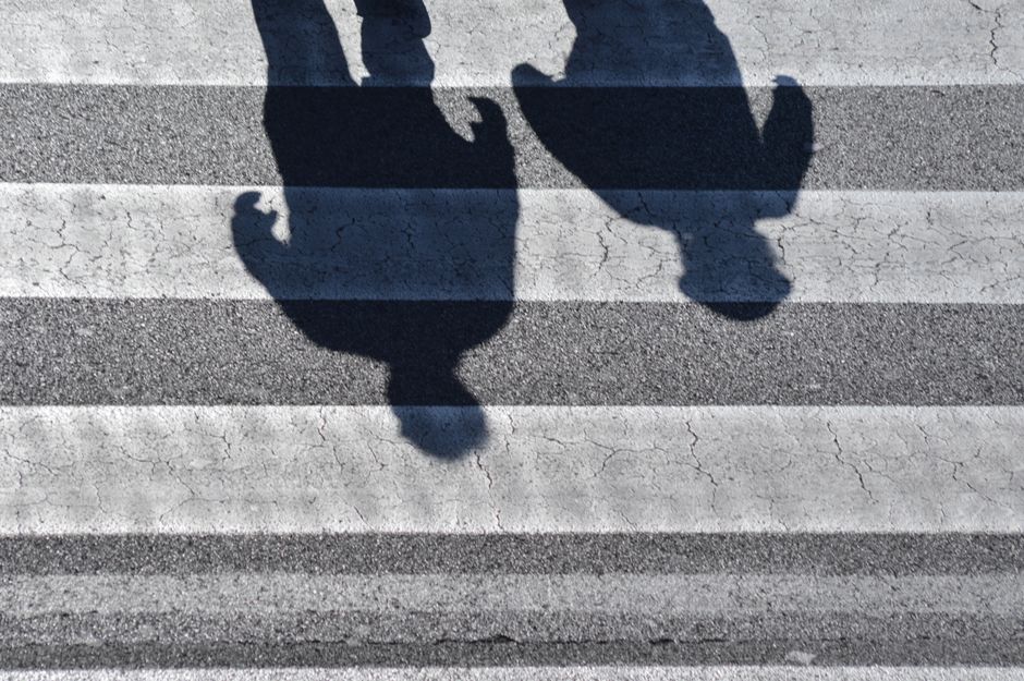 Top view shadows of people walking on an urban zebra crossing