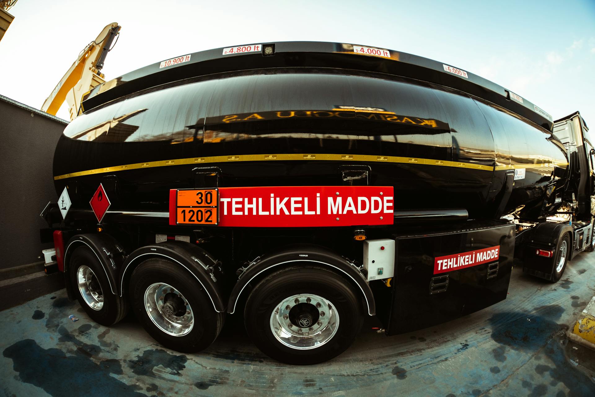 Wide-angle view of a black tank truck with hazard warning, highlighting its transportation purpose.