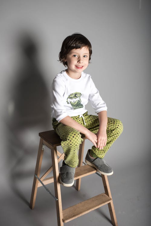 Boy Sitting on Brown Wooden A-frame Steps