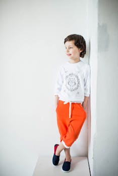 一个穿着鲜艳裤子和休闲上衣的时尚小男孩正在室内摆姿势