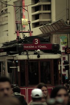 Iconic red tram in Taksim, Istanbul, surrounded by a busy urban crowd, reflecting vibrant city life.