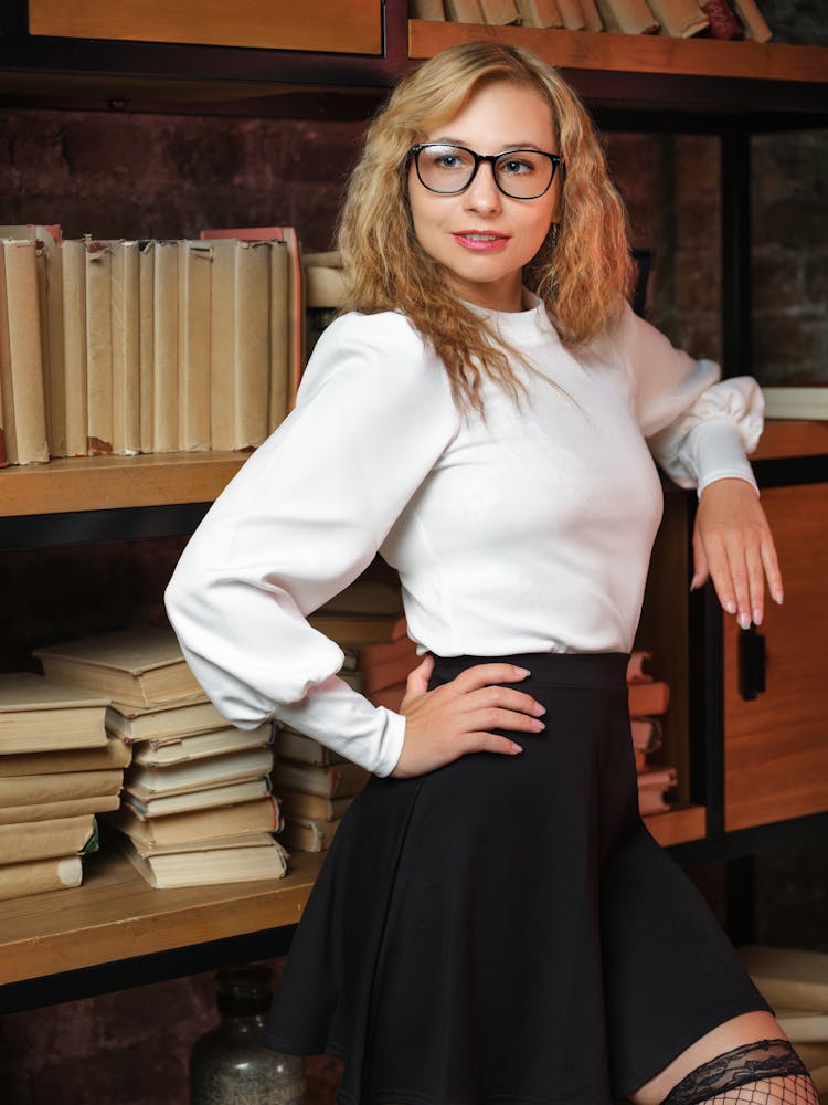 An Elegant Woman Standing Next To A Bookshelf 