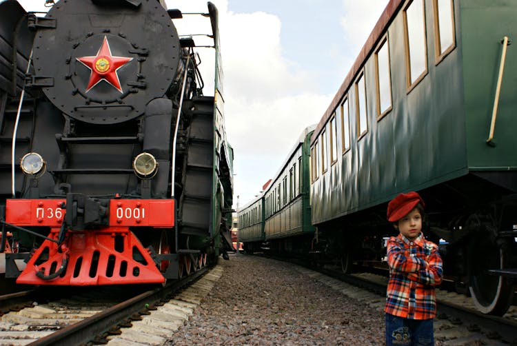 Boy Standing In Between Big Trains