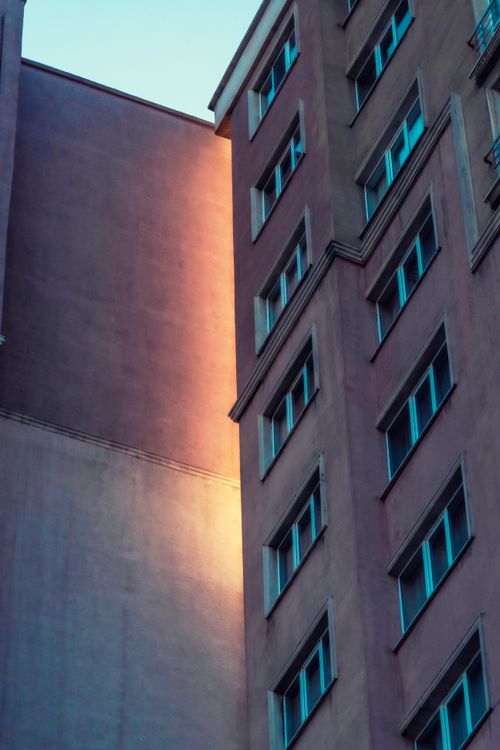 Free Low angle view of a modern apartment building with evening light casting a warm glow on its facade. Stock Photo
