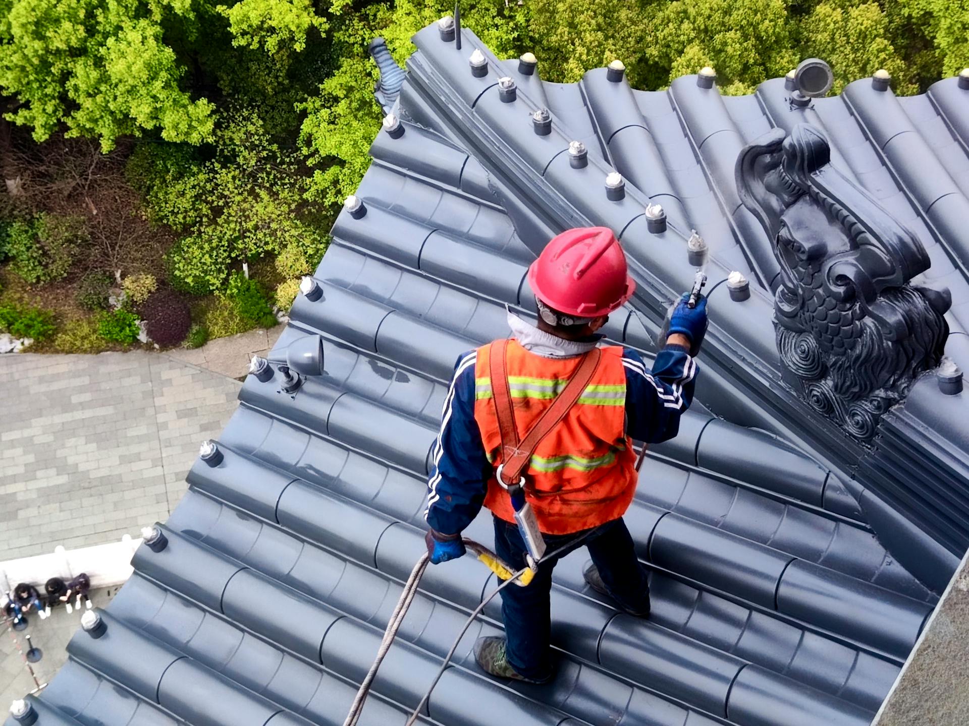 Roof worker in Hangzhou, China, uses safety gear while maintaining traditional temple roof.