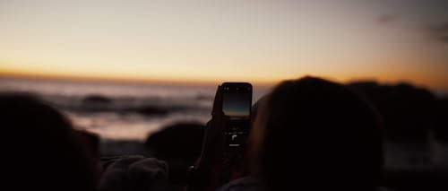 silhouette of taking a picture of a rocky sunset during golden hour
