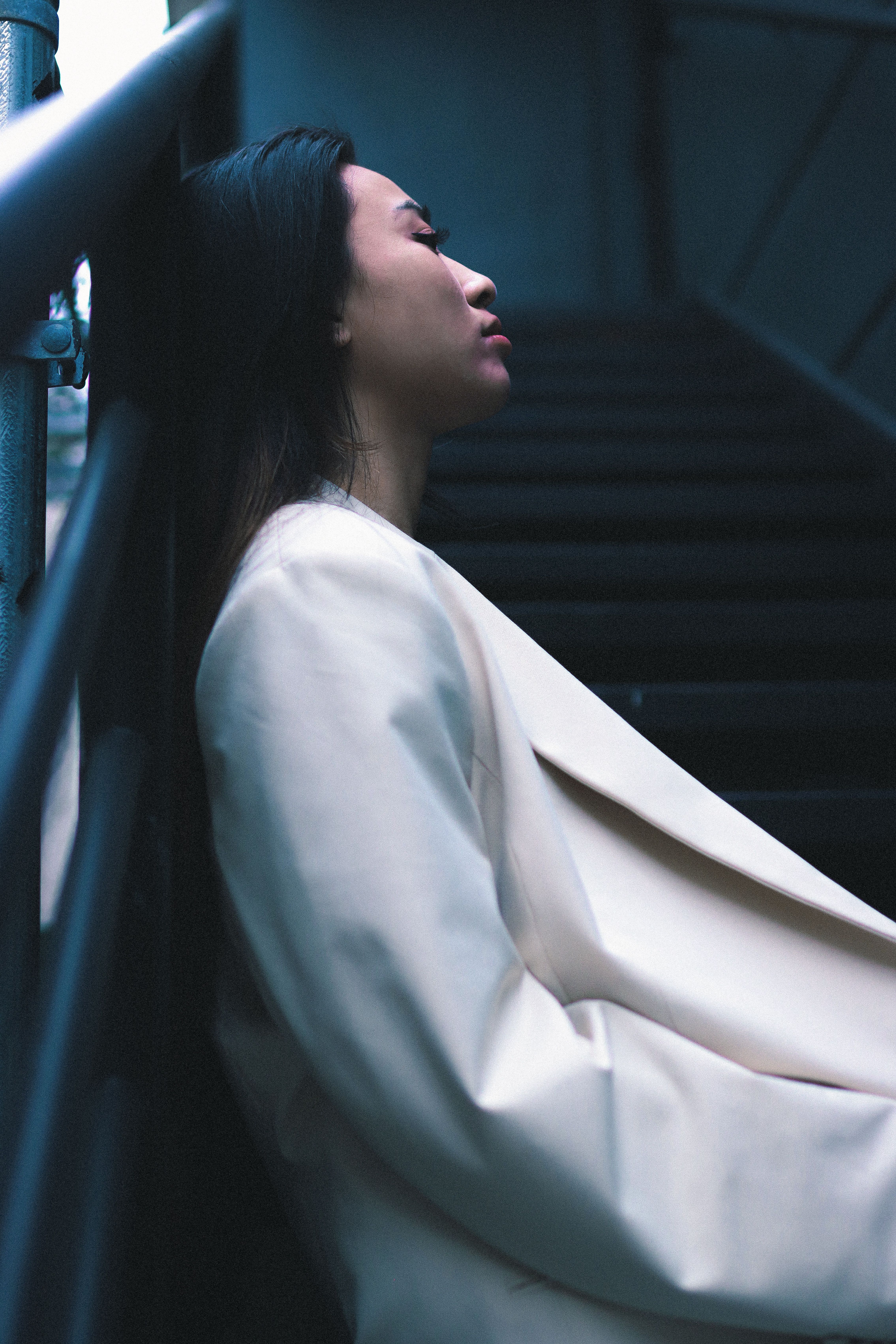 Side View of a Woman in a White Jacket Standing with Her Back against ...