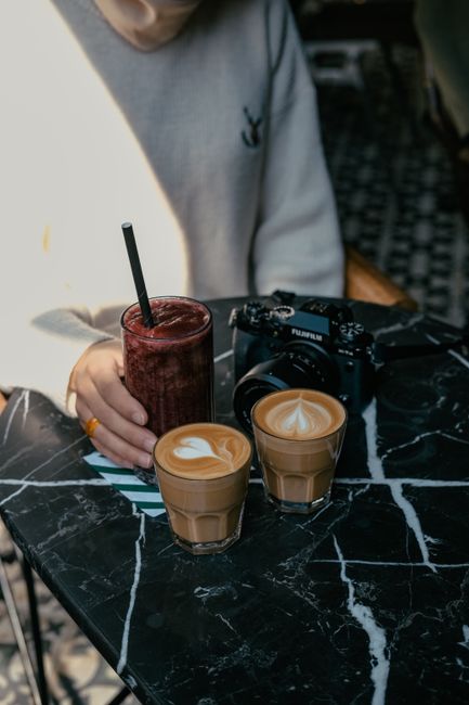 Stylish café table in İstanbul with coffees, smoothie, and camera on a black marble table.