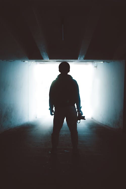 Silhouette of Man Standing in Tunnel Underground