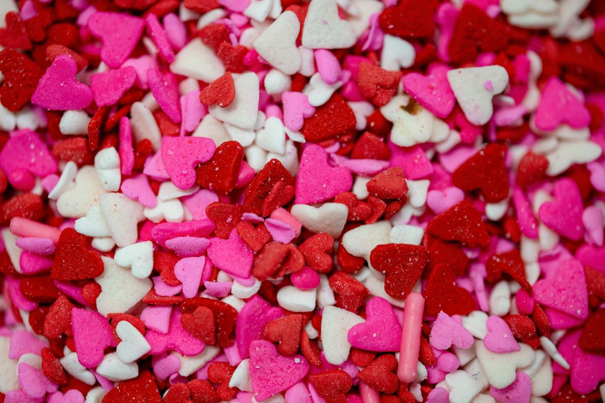 Bright close-up of heart-shaped candy sprinkles in red, pink, and white hues.