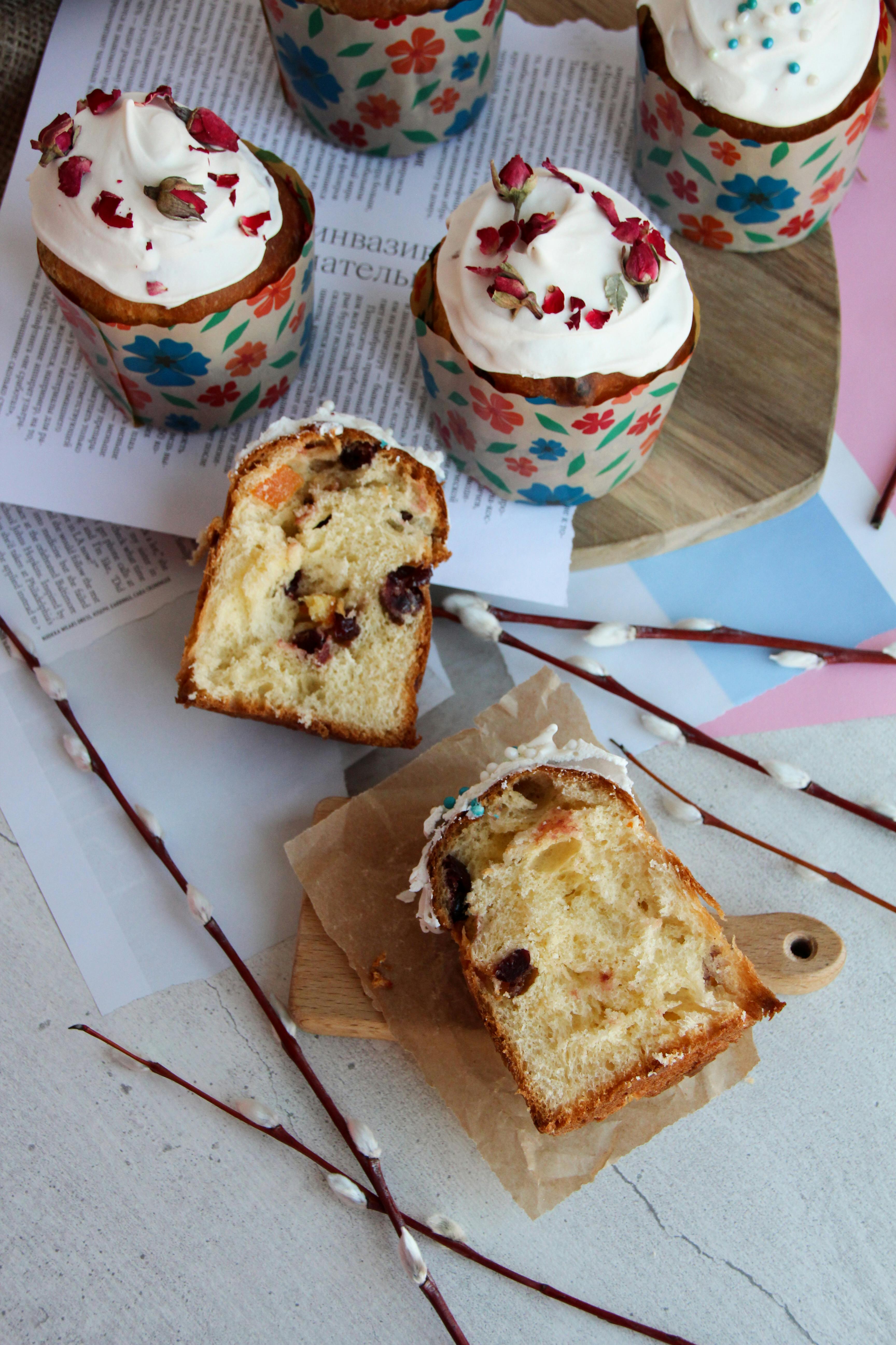 Top view of floral cupcakes with icing and dried fruits on a wooden tray.