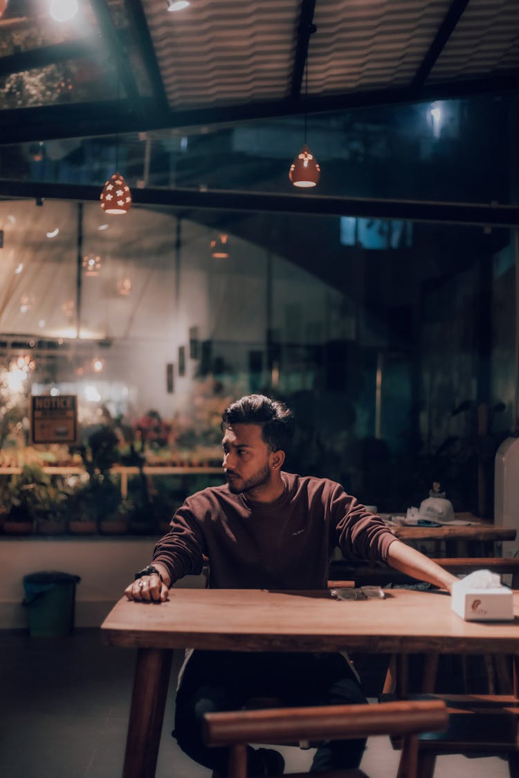 Man Sitting At The Table In A Restaurant Patio In The Evening 