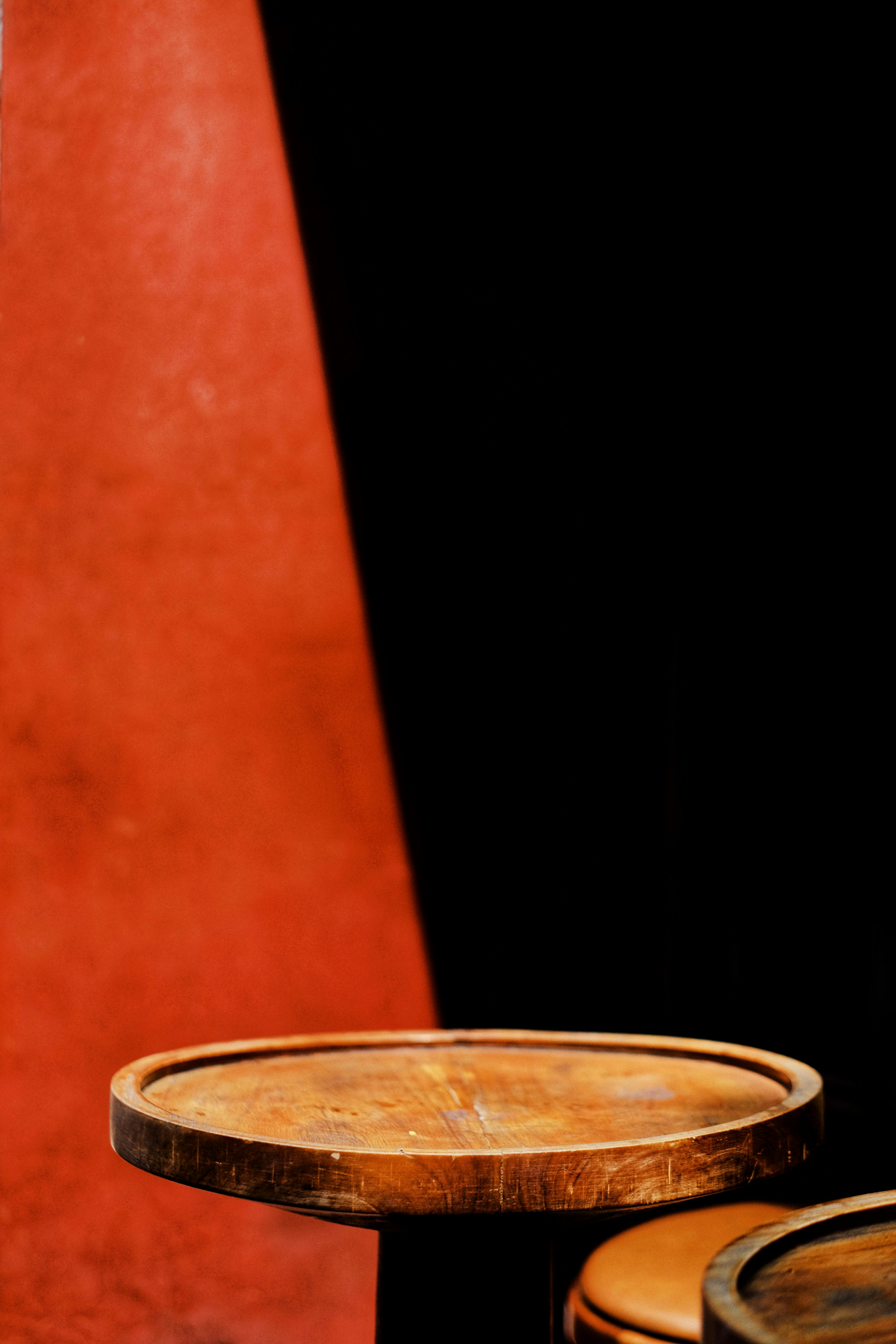 A minimalist wooden table placed against a textured red background, ideal for interior design themes.