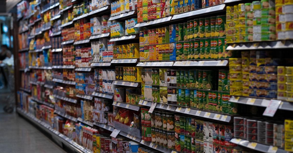 A supermarket aisle filled with various canned goods on shelves, showcasing retail diversity.