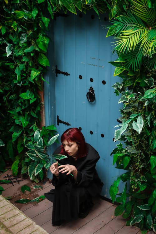Young Woman Crouching in Front of an Overgrown Door