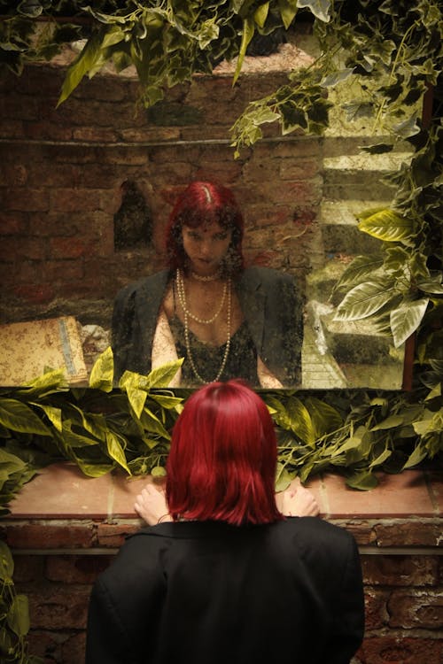Reflection of Woman with Dyed Hair in Mirror on Wall with Leaves around